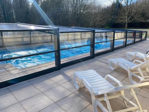 een groot zwembad met 2 stoelen en een tafel bij Logement insolite "Bubble jungle" in Saint-Évarzec