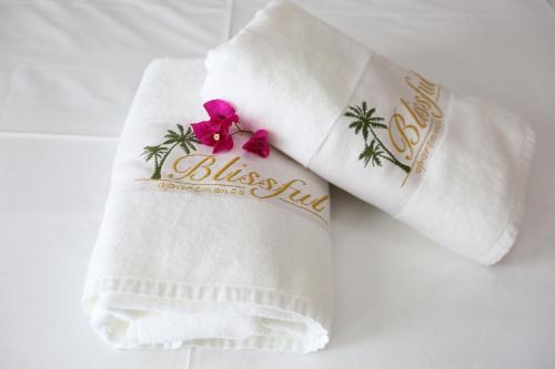 a white towel with a bliss club logo on it at Blissful Apartments in Sarandë