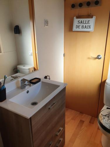 - une salle de bains avec un lavabo et un panneau indiquant la vente de cerveau dans l'établissement Mobil home dans camping, à Saillagouse