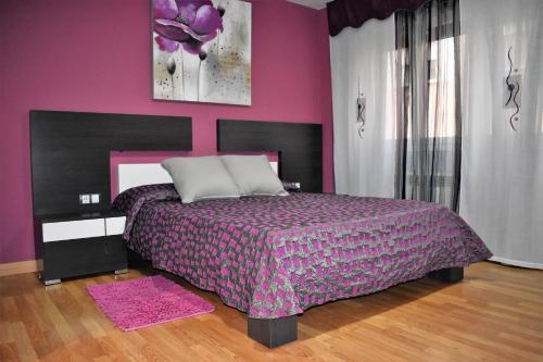 - une chambre avec un grand lit et un mur rose dans l'établissement Dinoapartamento, à Teruel