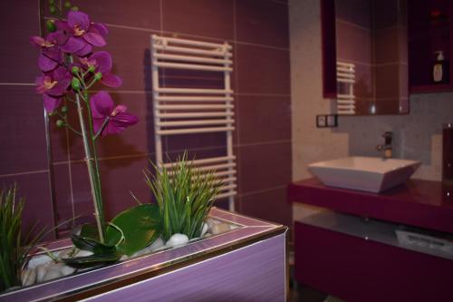 La salle de bains est pourvue d'un lavabo et de fleurs violettes dans un réservoir. dans l'établissement Dinoapartamento, à Teruel