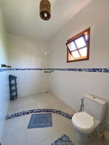 a bathroom with a toilet and a window at Casa Flamboaiã, Aluguel de Temporada, BA. 2022/23 in Guaibim