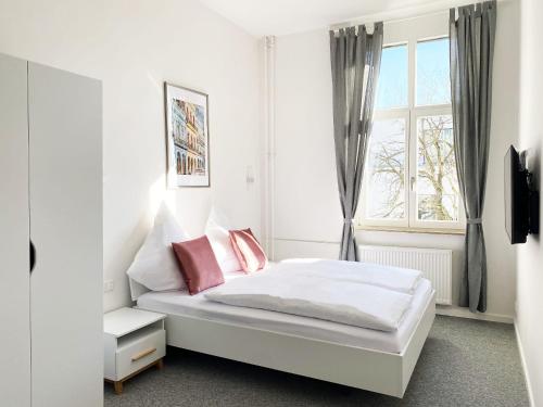 a white bedroom with a bed and a window at Best Boarding House in Hanau am Main