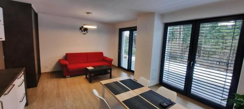 a living room with a red couch and a table at Apartmány Aktiv Lipno in Lipno nad Vltavou