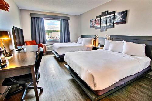a hotel room with two beds and a desk at Hôtel l'Empress in Rimouski