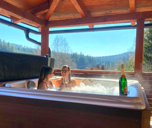 two women in a bath tub with a bottle of wine at Wellness Chalupa Horní Orlice in Králíky