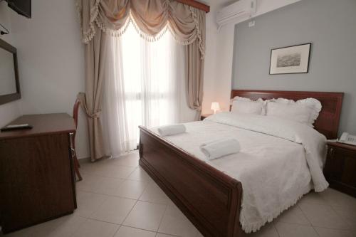 a bedroom with a large bed and a large window at Olympia Hotel in Sarandë