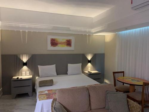 1 dormitorio con 1 cama, mesa y sillas en Flat Tropical en Manaos