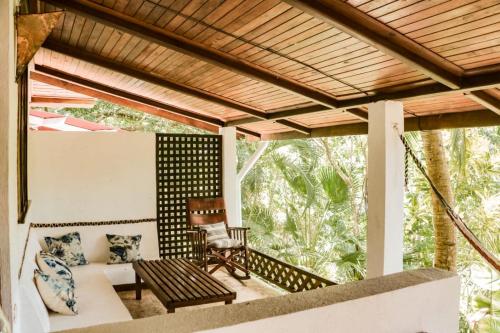 a screened in porch with a couch and a chair at Finca Los Caballos Montezuma in Montezuma