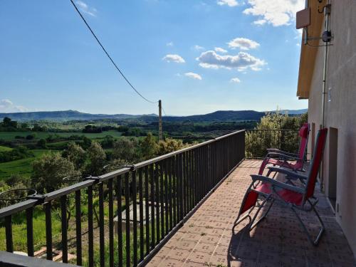 a balcony with two chairs and a view of the countryside at Cal Viudet Nou in Caserras