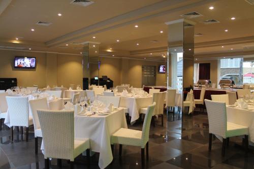 uma sala de jantar com mesas e cadeiras brancas em Novo Turismo Resort & Spa em Dili