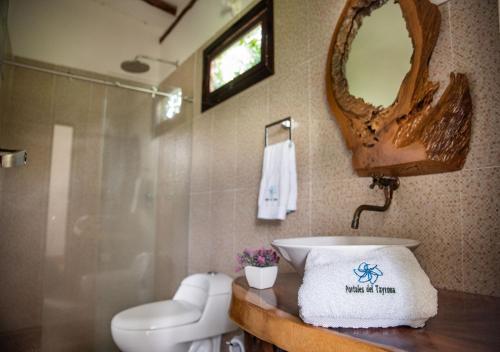 a bathroom with a sink and a toilet and a mirror at Portales del Tayrona Garden Hotel in Calabazo