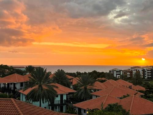 a sunset over a city with houses and palm trees at Blue Bay Apartments in Sint Michiel