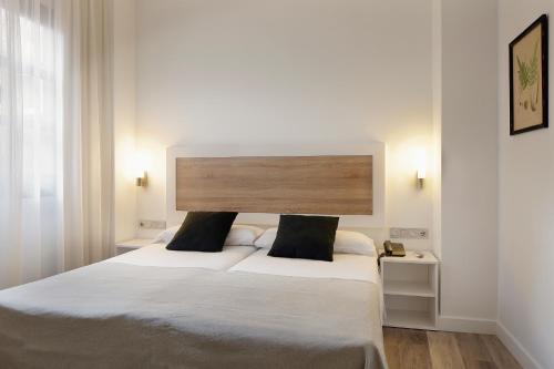 a bedroom with a large bed with white sheets at Hotel Santa Rosa, Blue Hoteles in Gijón