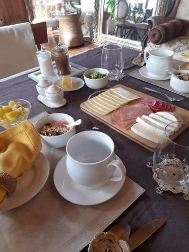 a table topped with plates and cups and cheese at Cabañas Puente Negro in Puente Negro