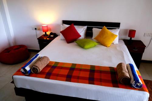 a bedroom with a large bed with colorful pillows at Wellé Wadiya Beach Villa in Kalpitiya