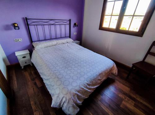 a bedroom with a bed with a white bedspread and a window at A Porteliña Casa Rural in Ambas Aguas