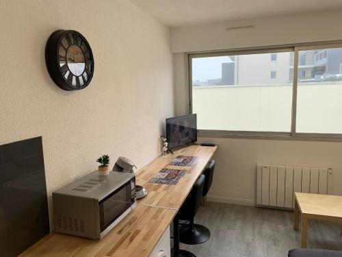 ein Büro mit einem Schreibtisch mit einem Computer und einer Uhr in der Unterkunft Studio entièrement rénové avec parking gratuit in Saint-Nazaire