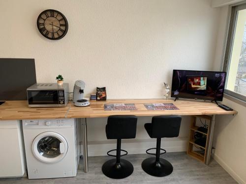 a wooden desk with three chairs and a microwave at Studio entièrement rénové avec parking gratuit in Saint-Nazaire