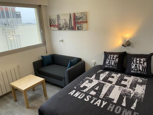 um quarto com uma cama, uma cadeira e uma janela em Studio entièrement rénové avec parking gratuit em Saint-Nazaire
