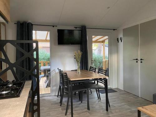 uma sala de jantar com uma mesa de madeira e cadeiras em MOBIL-HOME NEUF 2021 3CH 34 M2 em Saint-Cyprien