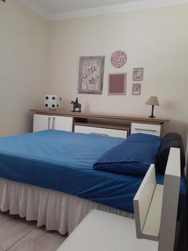 - une chambre avec un lit bleu et un bureau dans l'établissement CASA DE PRAIA COM PISCINA e AREA GOURMET, à Caraguatatuba