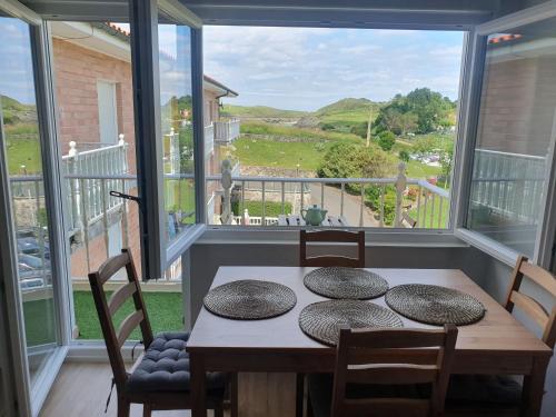 ein Esszimmer mit einem Tisch und Stühlen sowie einem großen Fenster in der Unterkunft Apartamento frente a la playa con vistas al mar en Barro, Llanes in Barro de Llanes