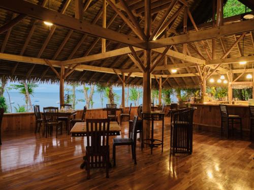 restauracja z drewnianymi podłogami, stołami i krzesłami w obiekcie Copa De Arbol Beach & Rainforest Resort w mieście Bahía Drake