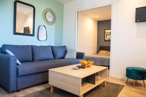 ein Wohnzimmer mit einem blauen Sofa und einem Tisch in der Unterkunft Bons Baisers du Touquet - Le Parc in Cucq
