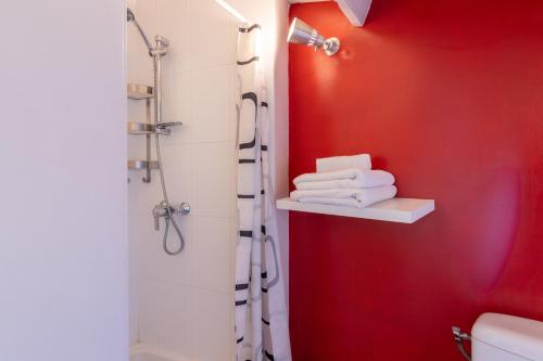La salle de bains est pourvue d'une douche et d'un mur rouge. dans l'établissement Maison chaleureuse-Grand jardin-Proche Saumur, à Parnay