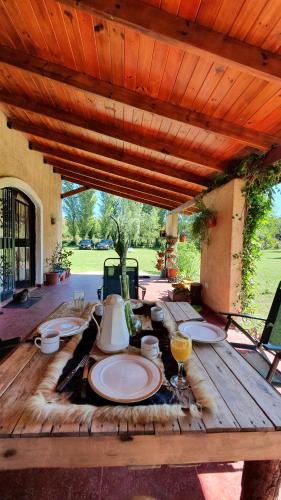 a wooden table with plates and wine glasses on it at HERMOSA CASA con 4000mts de PARQUE en las SIERRAS DE CORDOBA in José de la Quintana