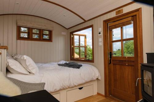 a bedroom with a bed and a tv and windows at Luxury, rural Shepherds Hut with hot tub nr Bath in Bristol