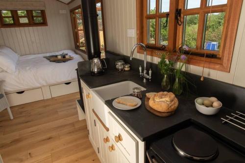 a kitchen with a counter with a sink and a bed at Luxury, rural Shepherds Hut with hot tub nr Bath in Bristol