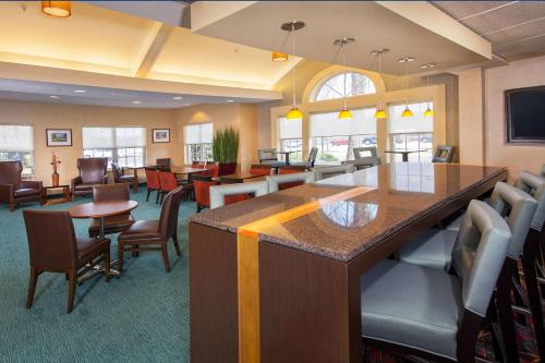 a waiting room with tables and chairs and a bar at Sonesta ES Suites Charlottesville University in Charlottesville
