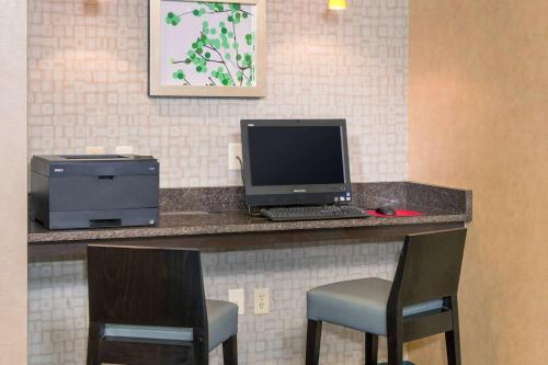 a desk with a computer and a printer and two chairs at Sonesta ES Suites Charlottesville University in Charlottesville