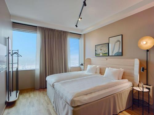 a bedroom with a large bed and large windows at Scandic Örebro Central in Örebro