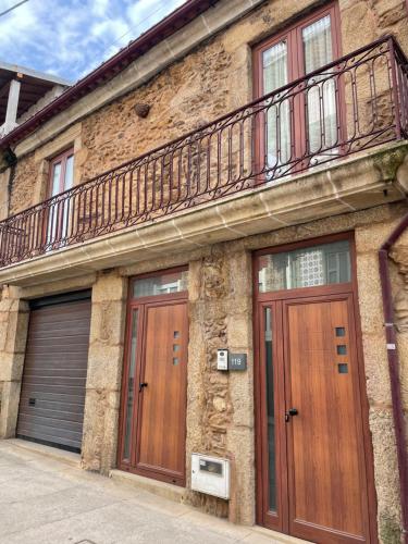 a brick building with two doors and a balcony at Casa da Rua histórica, Cabeceiras de Basto T3 in Cabeceiras de Basto