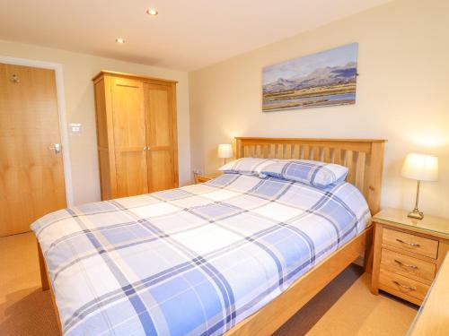 a bedroom with a bed with a blue and white comforter at Taliesin in Porthmadog