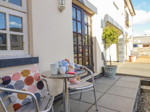a patio with two chairs and a table with cups on it at Taliesin in Porthmadog