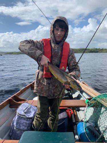 a woman is holding a fish in a boat at Ryan's River Lodge B&B in Cong