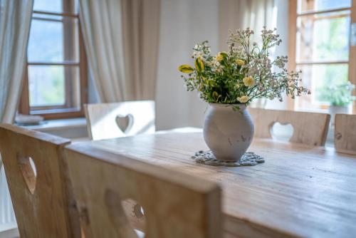 a vase with flowers sitting on a wooden table at Country House Trata in Kranjska Gora