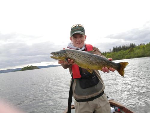 a man holding a brown trout on a lake at Ryan's River Lodge B&B in Cong