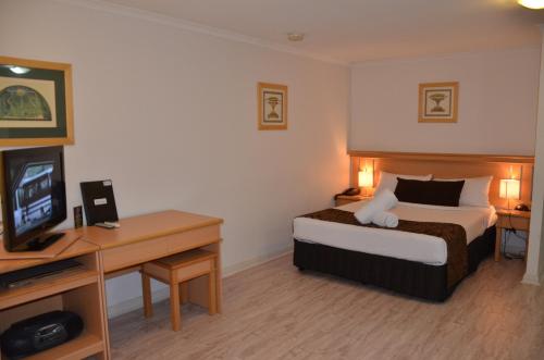 a hotel room with a bed and a desk with a television at Napoleon On Kent in Sydney