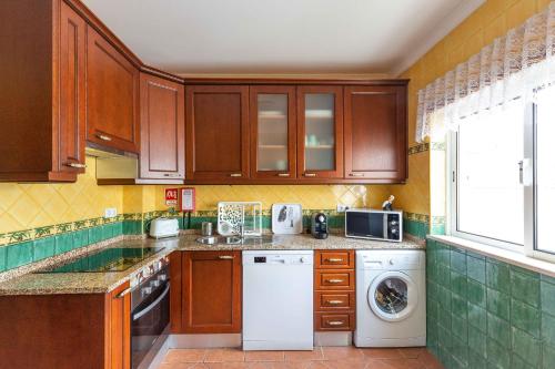 a kitchen with wooden cabinets and a washer and dryer at Villa Marquez Apartments in Vila Real de Santo António