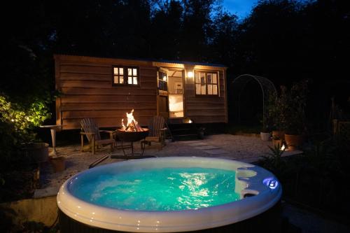 a hot tub in front of a cabin with a fireplace at Luxury, rural Shepherds Hut with hot tub nr Bath in Bristol