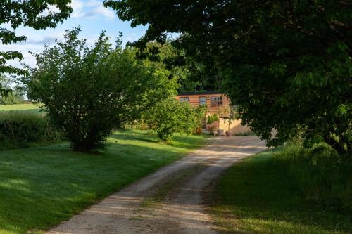 a dirt road with trees and a house in the distance at Luxury, rural Shepherds Hut with hot tub nr Bath in Bristol