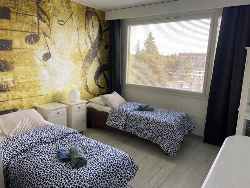 two beds in a room with a window and two shoes at M Apartments Tesomankuja in Tampere