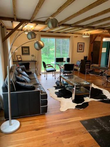 a living room with a black leather couch and a table at Harpersfield House /North West Catskills + sauna in Jefferson