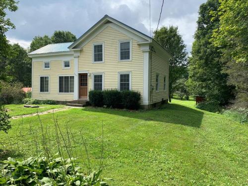 a white house on a grassy yard with trees at Harpersfield House /North West Catskills + sauna in Jefferson
