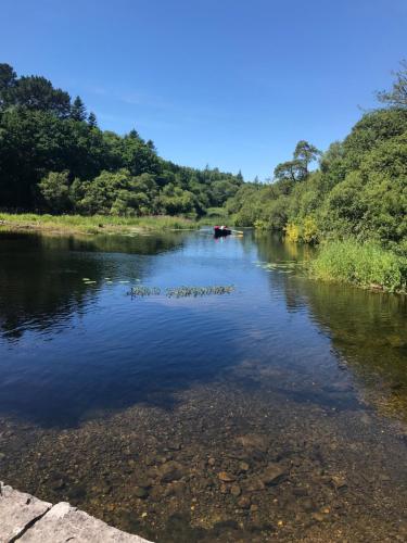 a river with a boat in the middle at Ryan's River Lodge B&B in Cong